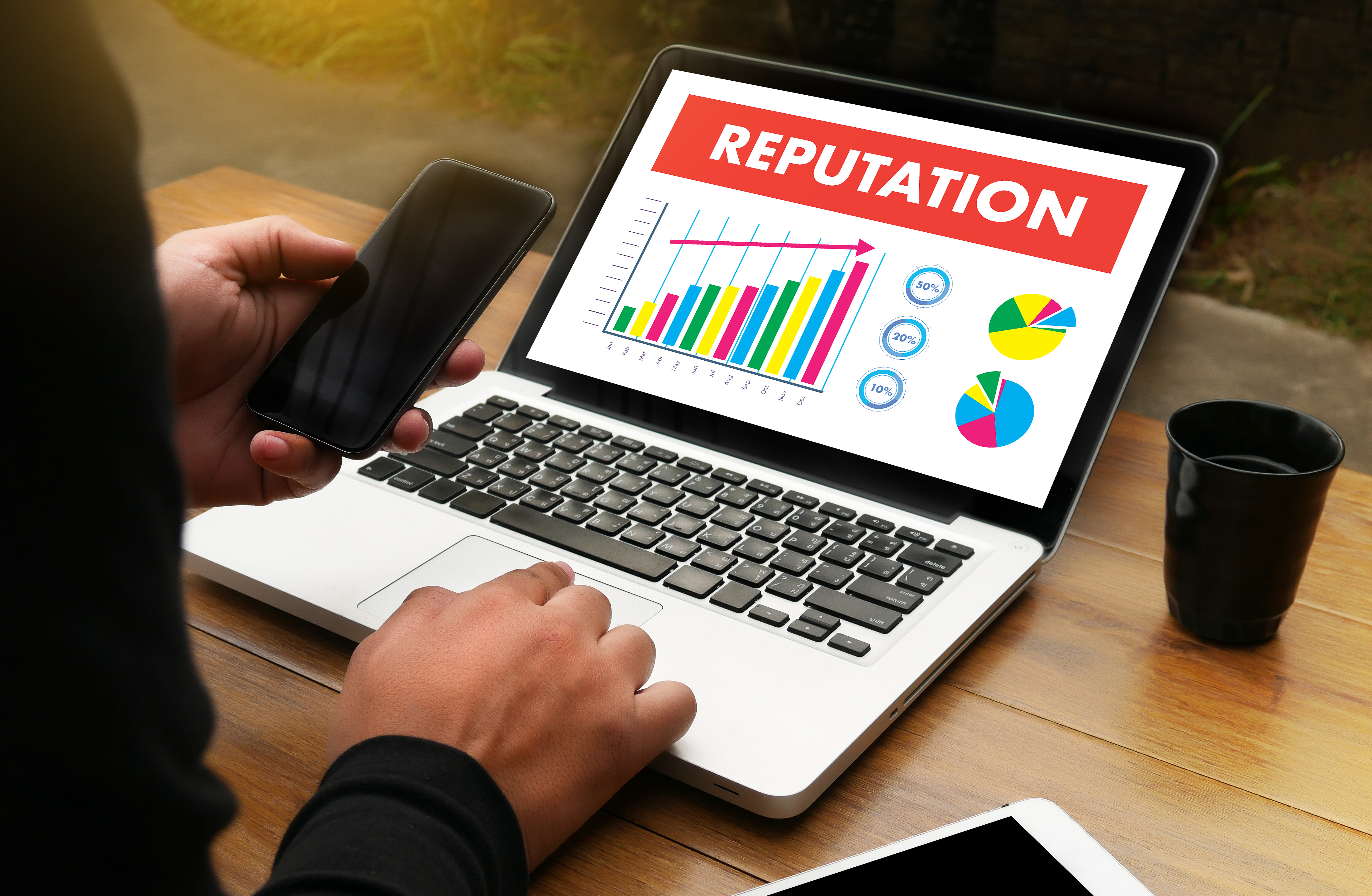 photo of a person at a laptop showing a bar graph titled reputation with an upwards trend